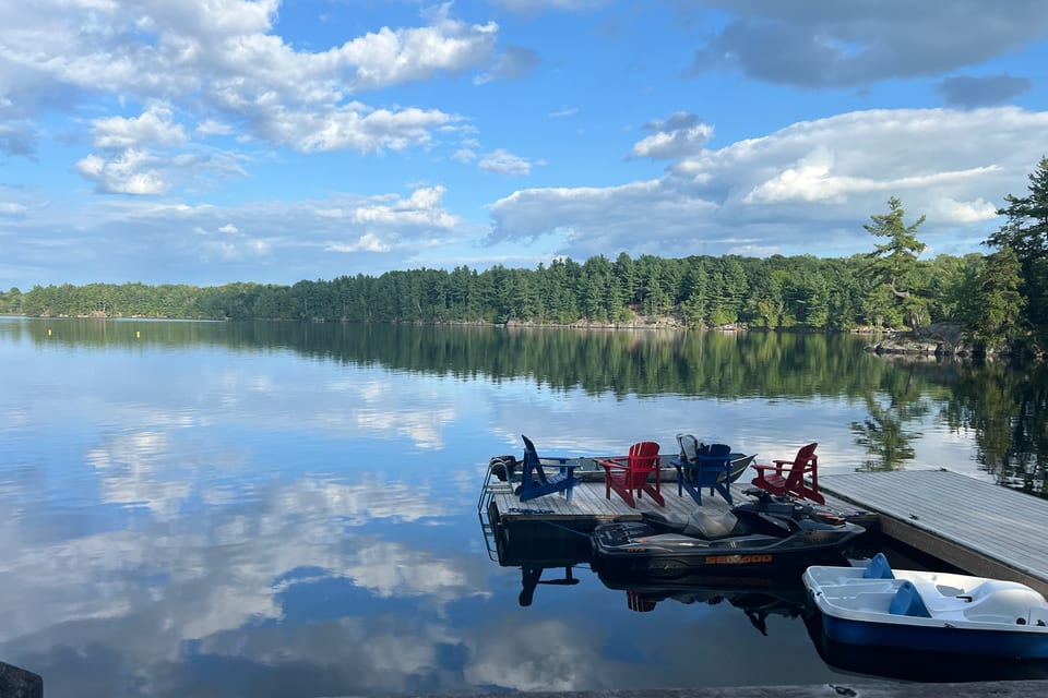 Chairs arranged on a dock beside a quiet lake.