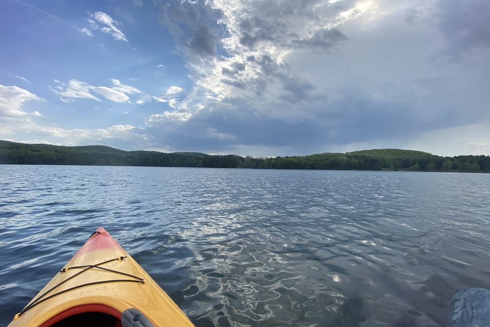 A kayak crossing a lake surrounded by low forest.