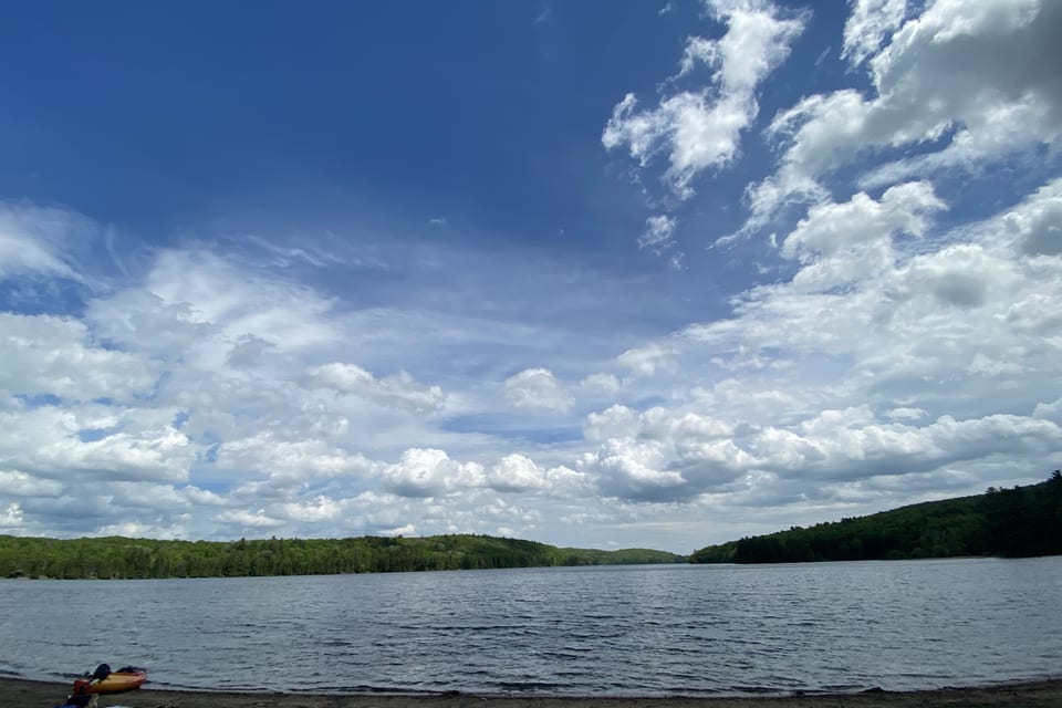 A kayak resting at the edge of a wide lake.