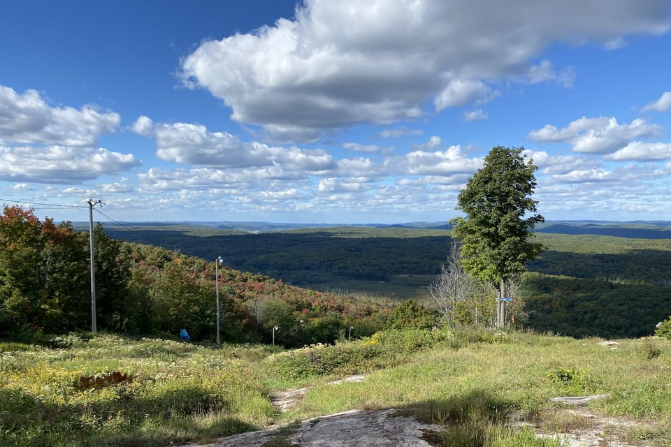 A mountain path beneath bright clouds and open sky.