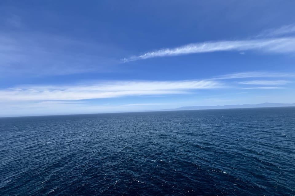 Open blue water meeting a wide, cloud-streaked horizon.