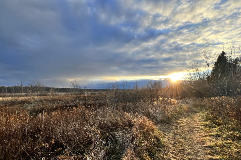 A winter field and narrow path under a setting sun.