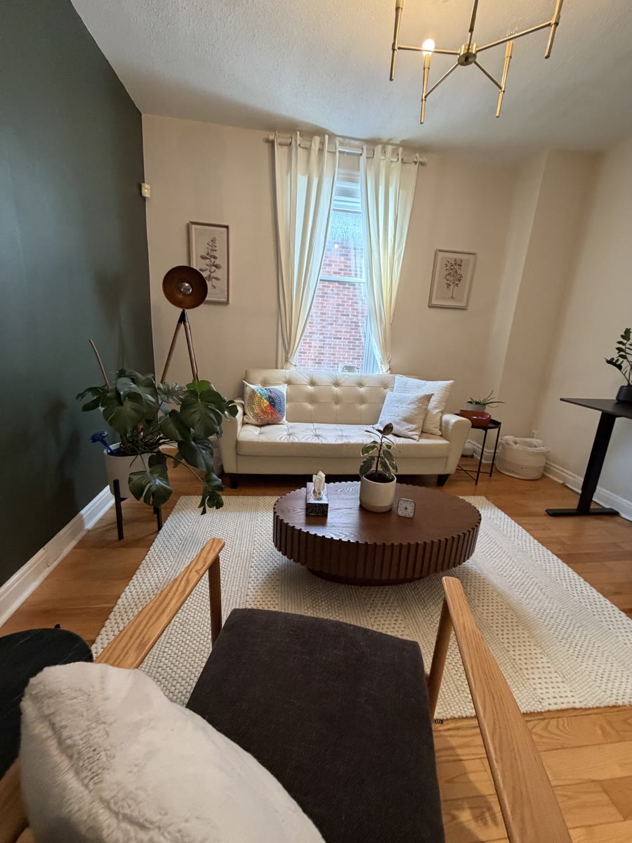 The Ripple Effect therapy room at 9 Melrose Ave in Hintonburg: cream couch, green accent wall, plants, and warm light.